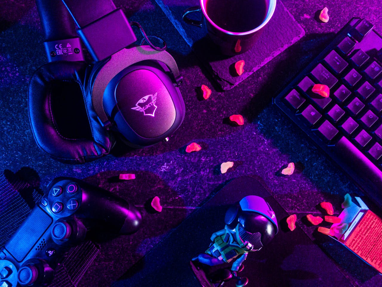 gallery-2 Colorful flat lay of gaming gear including headset, controller, and keyboard under vibrant lighting.